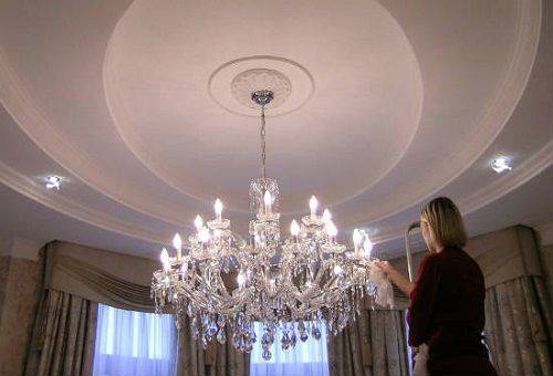 femeia curăță un candelabru de cristal