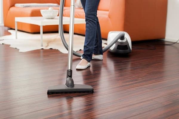 Femeie care aspira pardoseala laminată în sufragerie