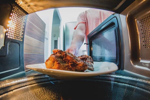 Omul pune carne în cuptorul cu microunde
