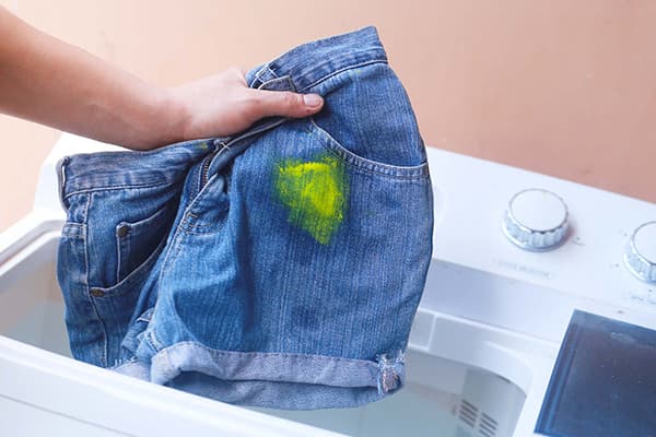 Spălați pantaloni scurți cu o pată din vopsea