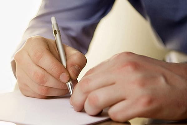 Ένας άνθρωπος γράφει σε ένα σημειωματάριο