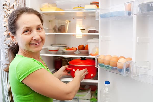 Femeia pune tigaia la frigider