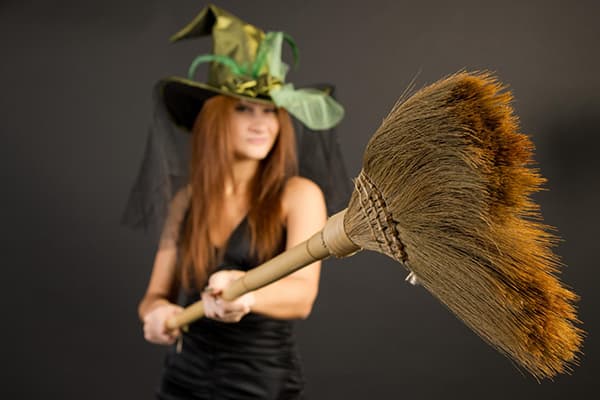 Fată în costum de vrăjitoare cu mătură